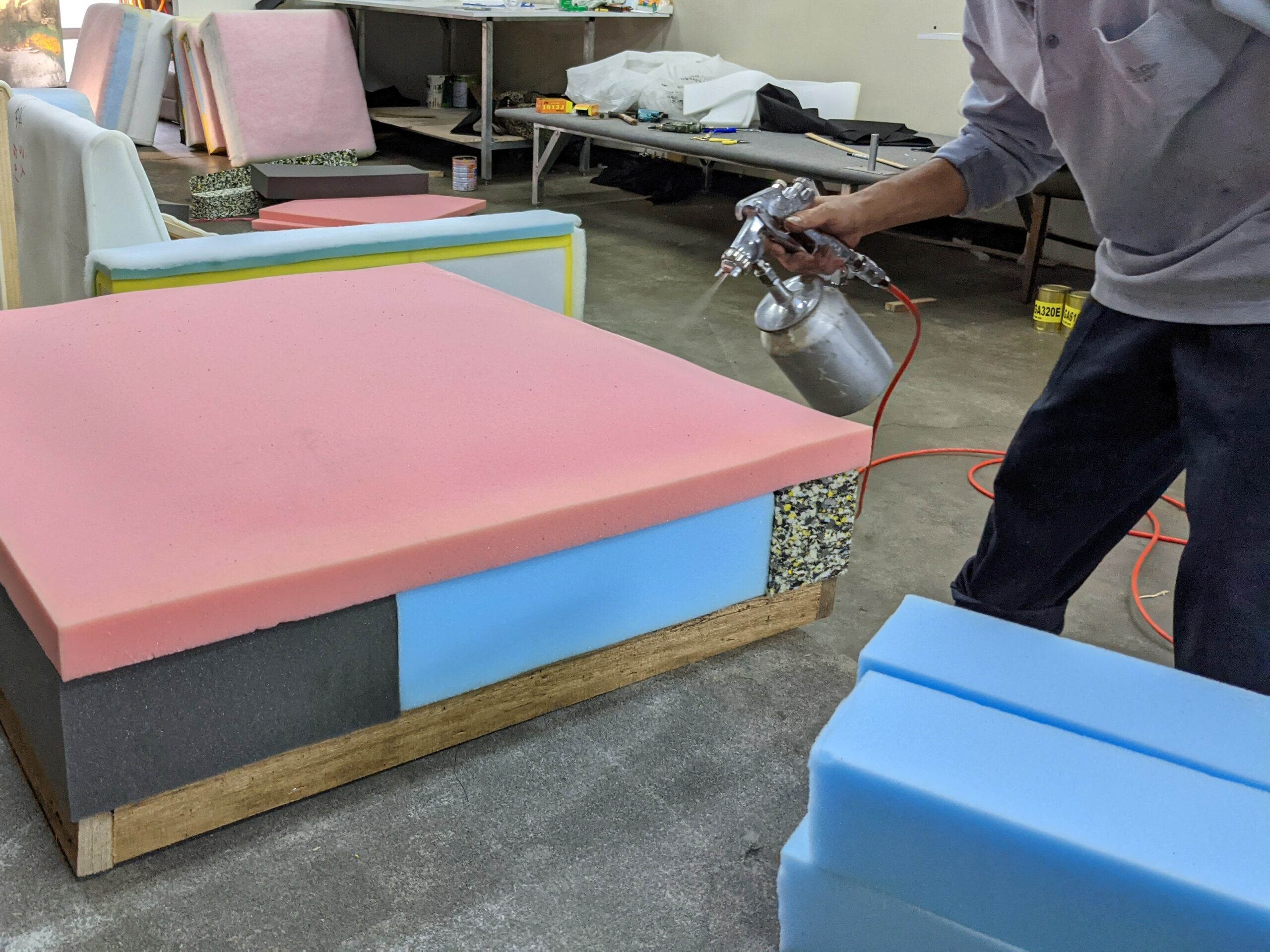 師傅泡綿貼合完成的椅墊外層噴上環保黏著劑，準備再貼上絲棉 by SOFA SOFA沙發工廠